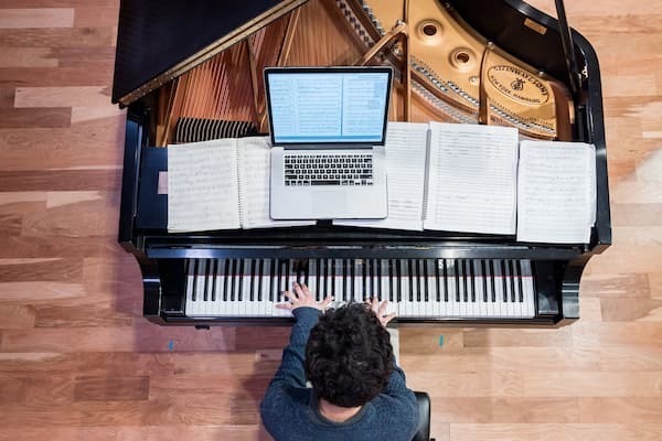 Overhead Photo Of A Student Playing The Piano While Composing Music